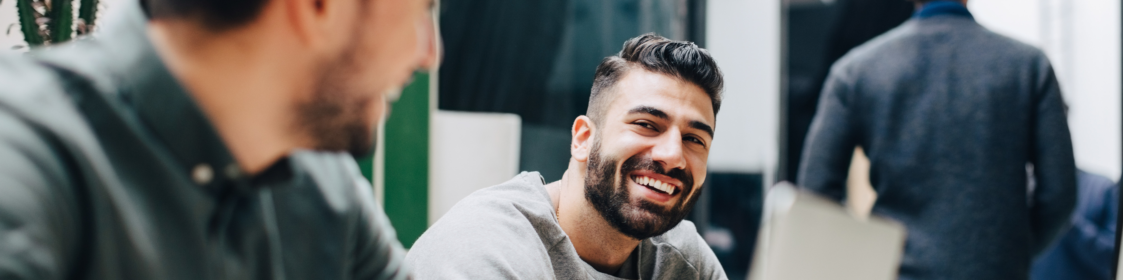 Portrait image of Man with dark brown beard and grey shirt smiling at coworker, friend, colleague in office setting, Q3 2021, TAA NA US - Preparer