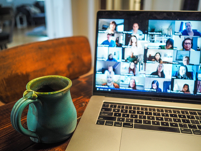 Zoom call on a laptop with coffee mug next to it on table