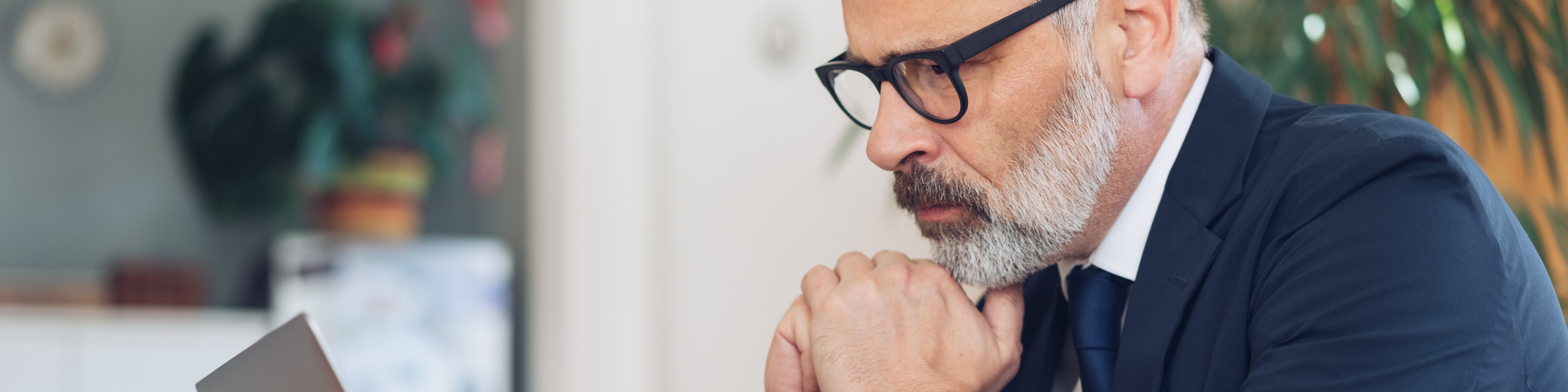 mature man looking at laptop and thinking