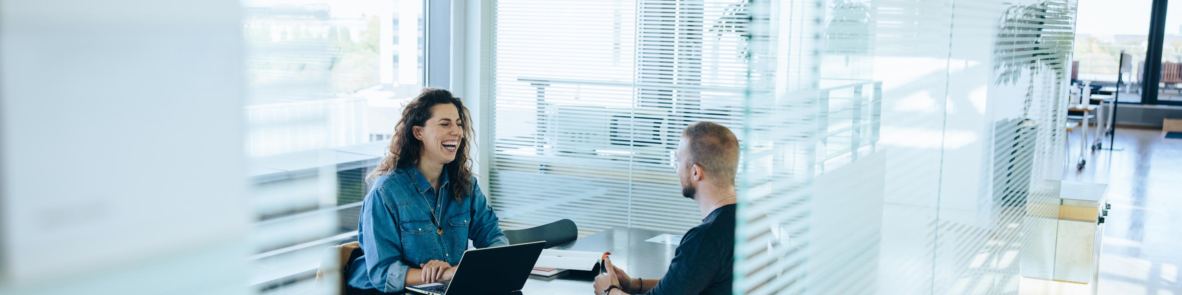 a businesswoman laughing while interviewing a potential candidate in an office setting