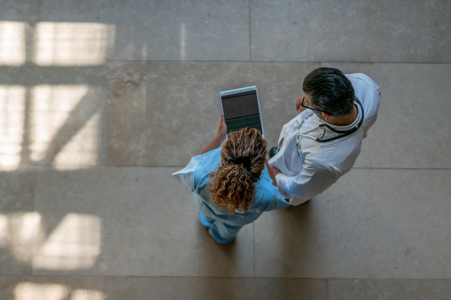 Female nurse showing information to doctor on tablet.