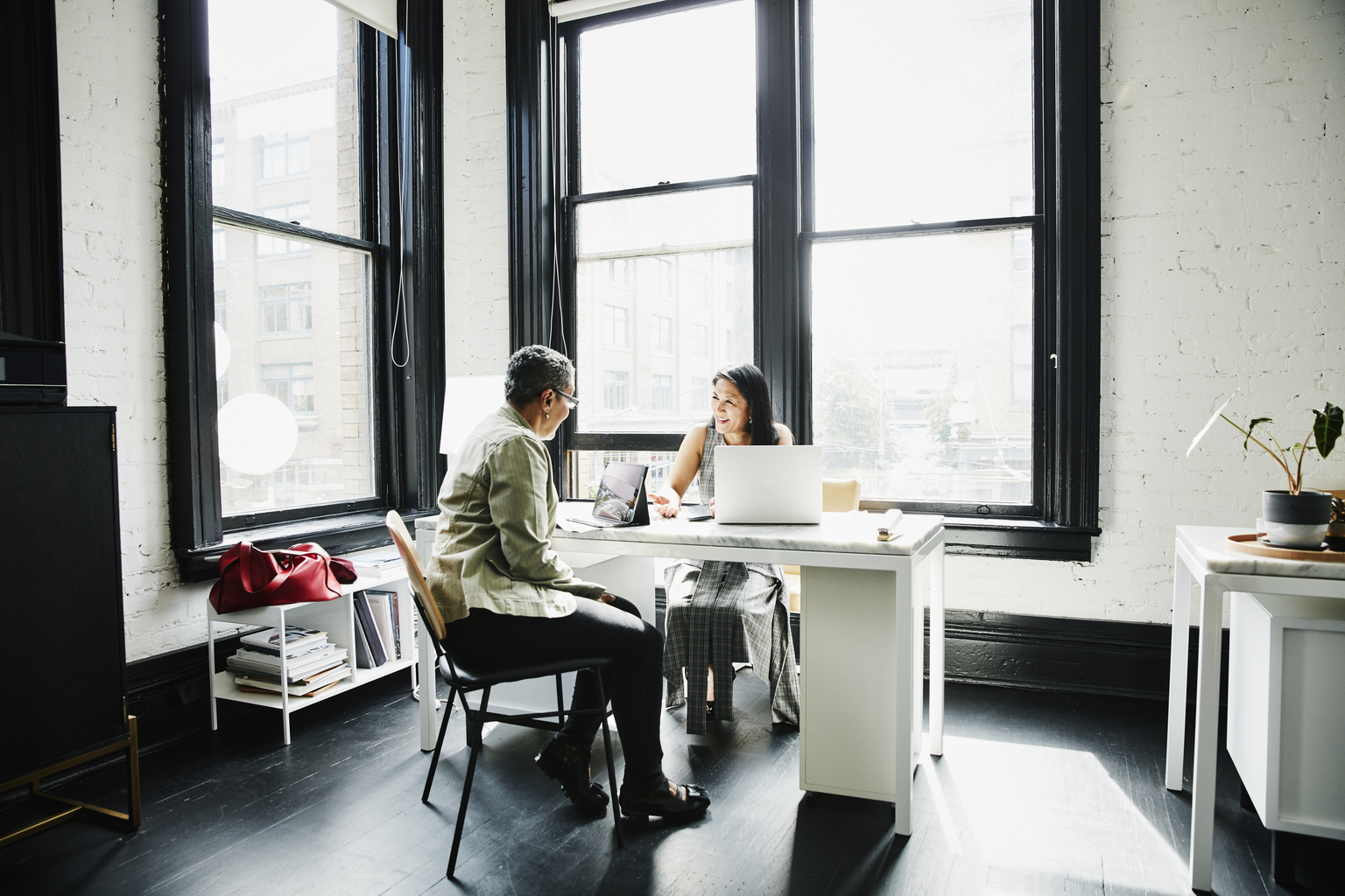 Smiling mature female business owner in discussion with financial advisor at desk in office