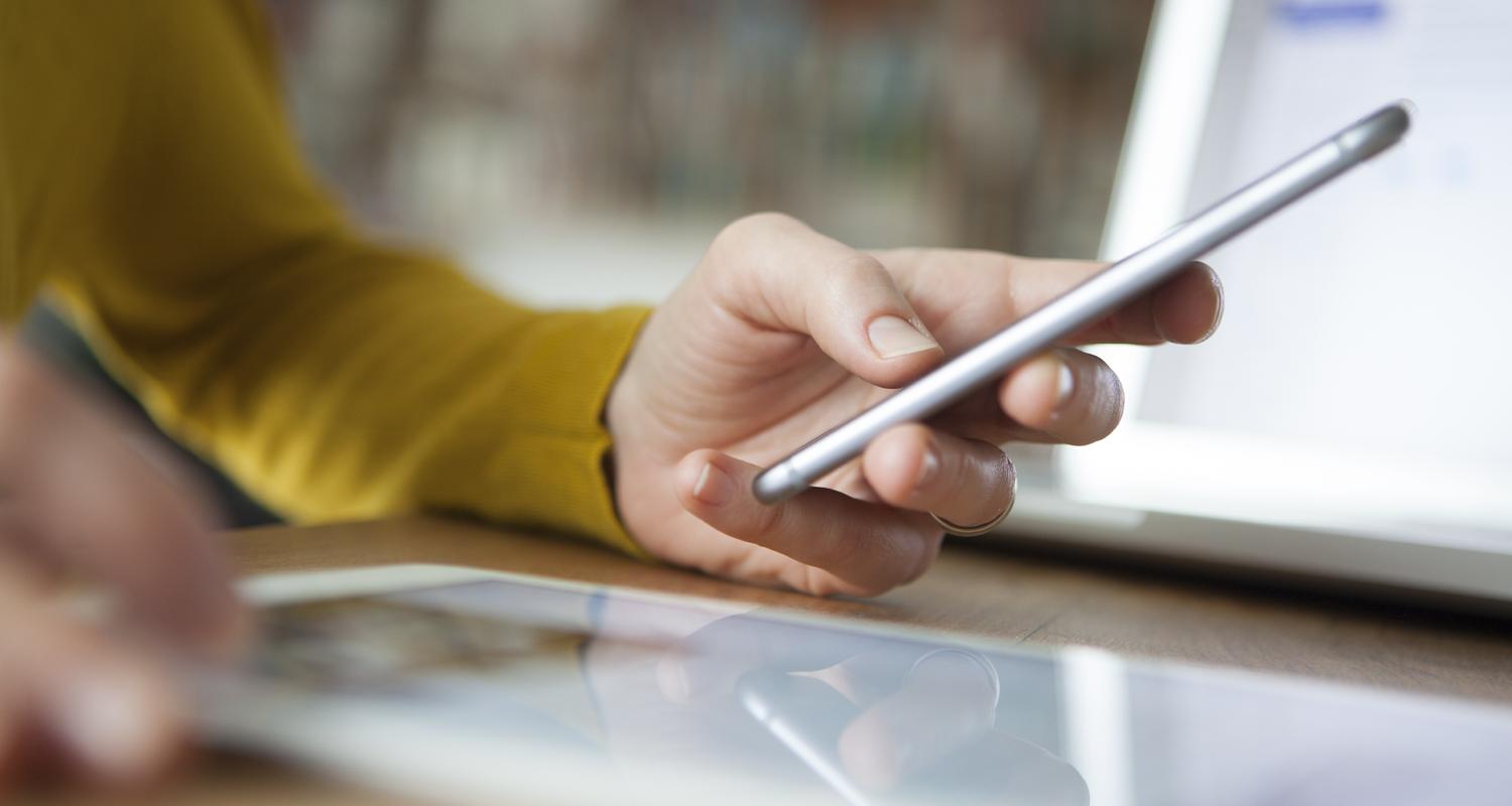 Lifestyle image of man with wedding ring holding his phone wearing mustard yellow sweater, reflection, Q3 2021, TAA NA US - Preparer