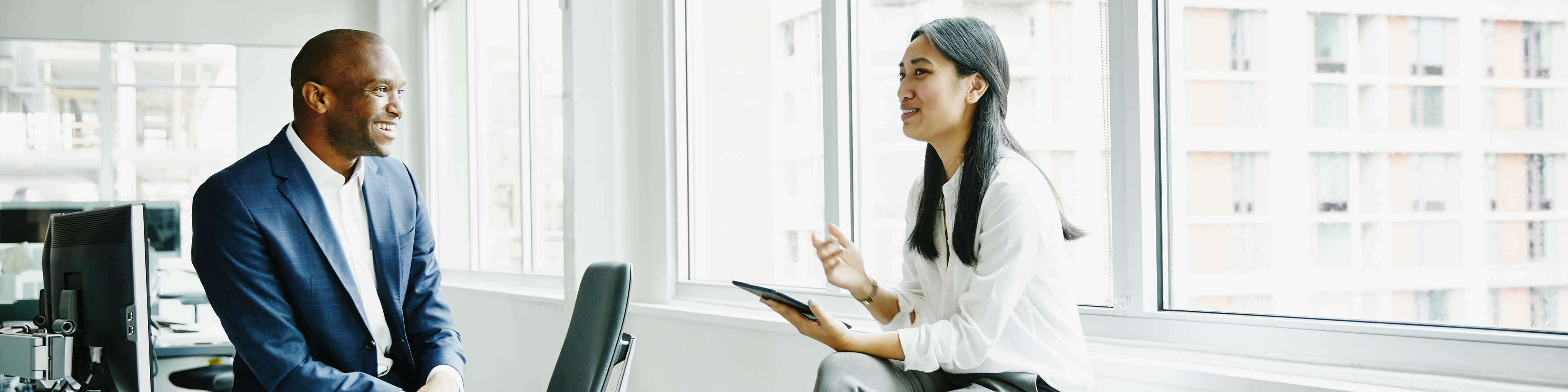 Smiling businessman and businesswoman discussing project at office workstation