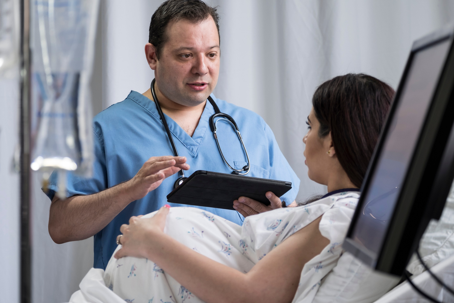 Doctor with tablet speaking with pregnant patient