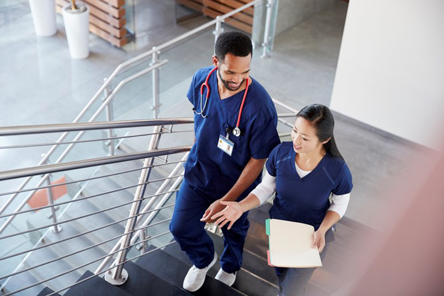 Two nurses walking up stairs in a hospital