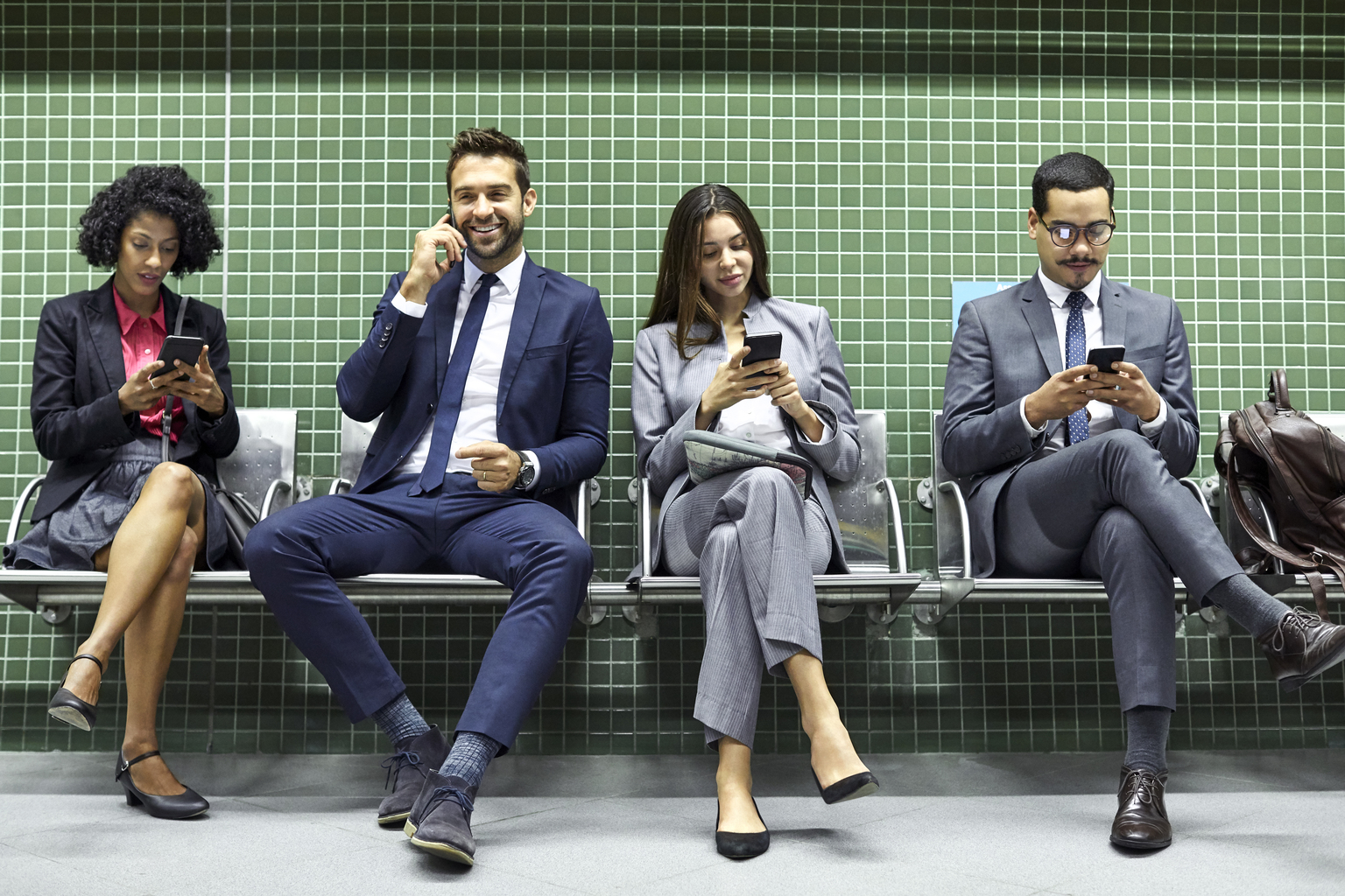 Full length of professionals using smart phones while waiting at subway station