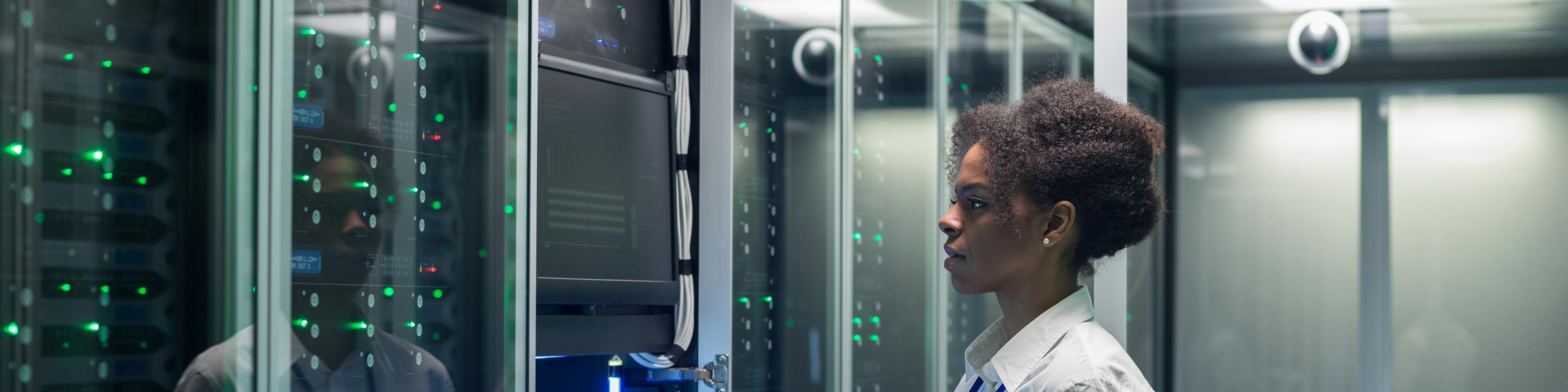 a female employee in a data center holding a tablet and inspecting servers