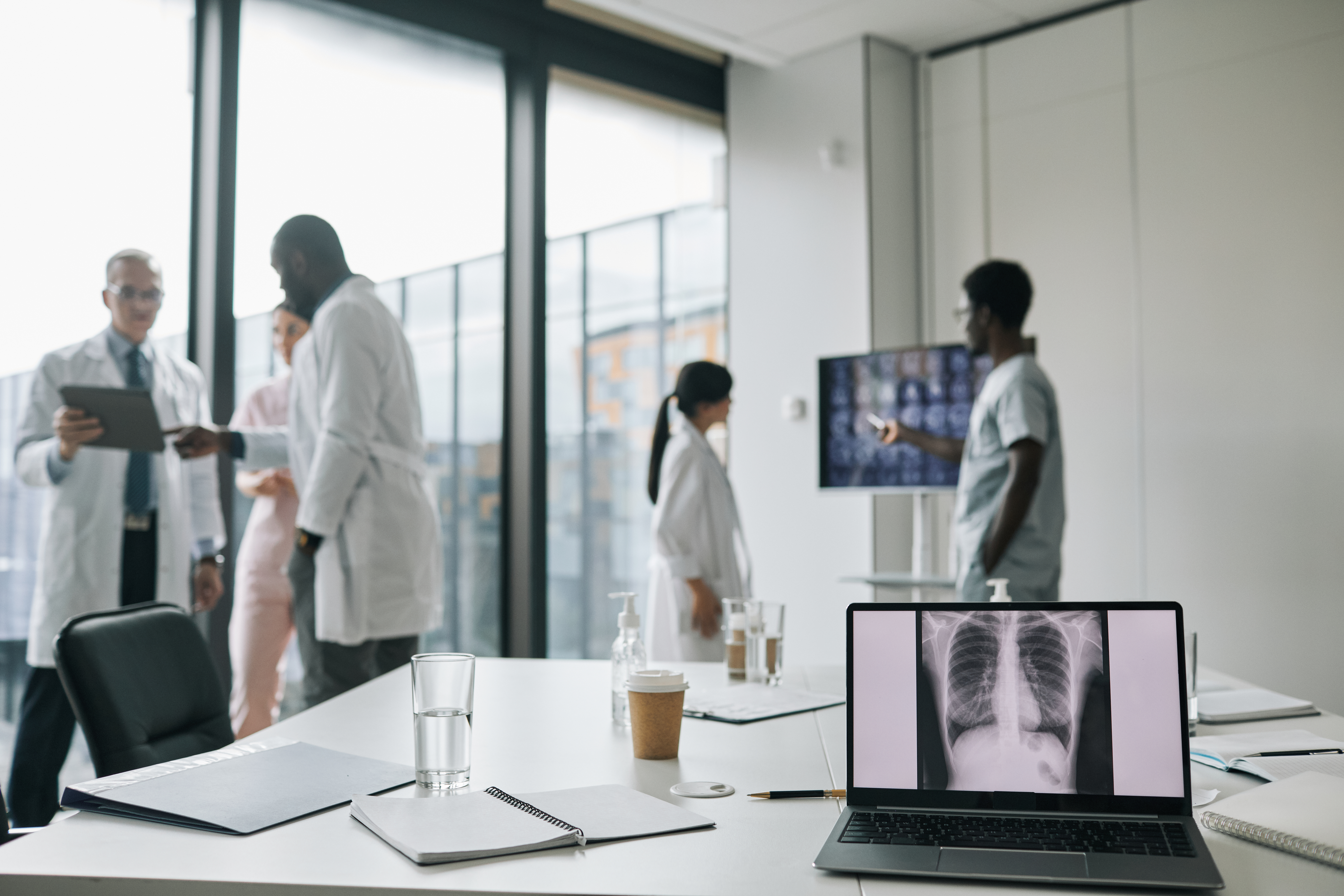 Medical imaging on laptop screen with healthcare workers in background