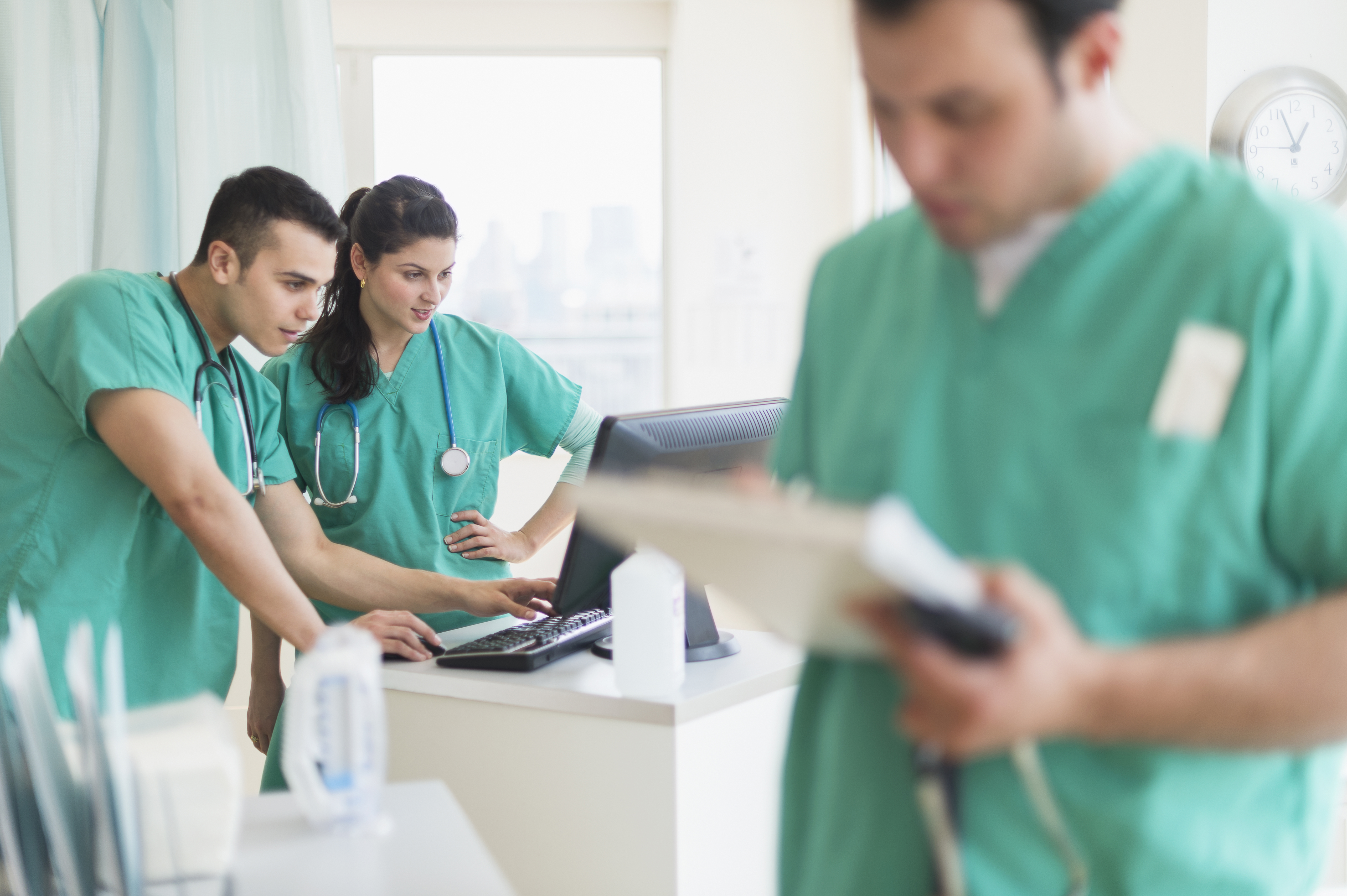 Young male and female Hispanic nurses working in hospital - another angle.