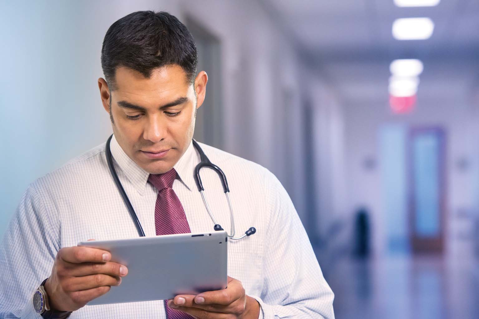 doctor paused in hallway looking at tablet