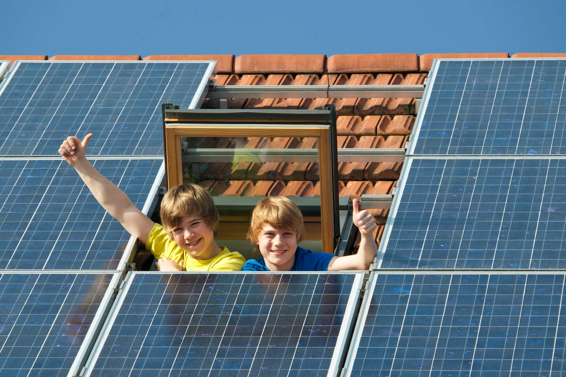 two young boys on a roof top with solar panels