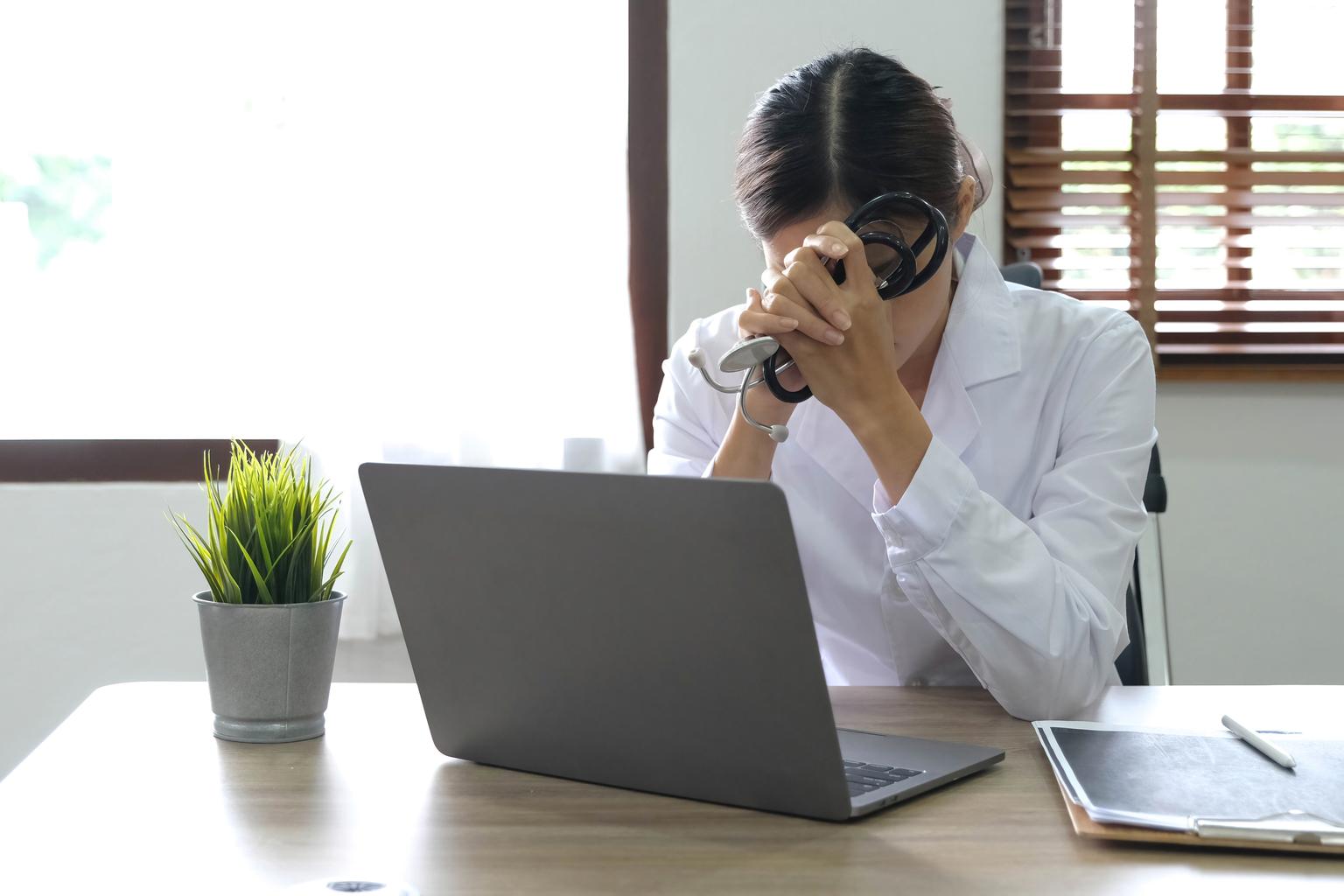 Health care professional sitting at desk, slumped in frustration