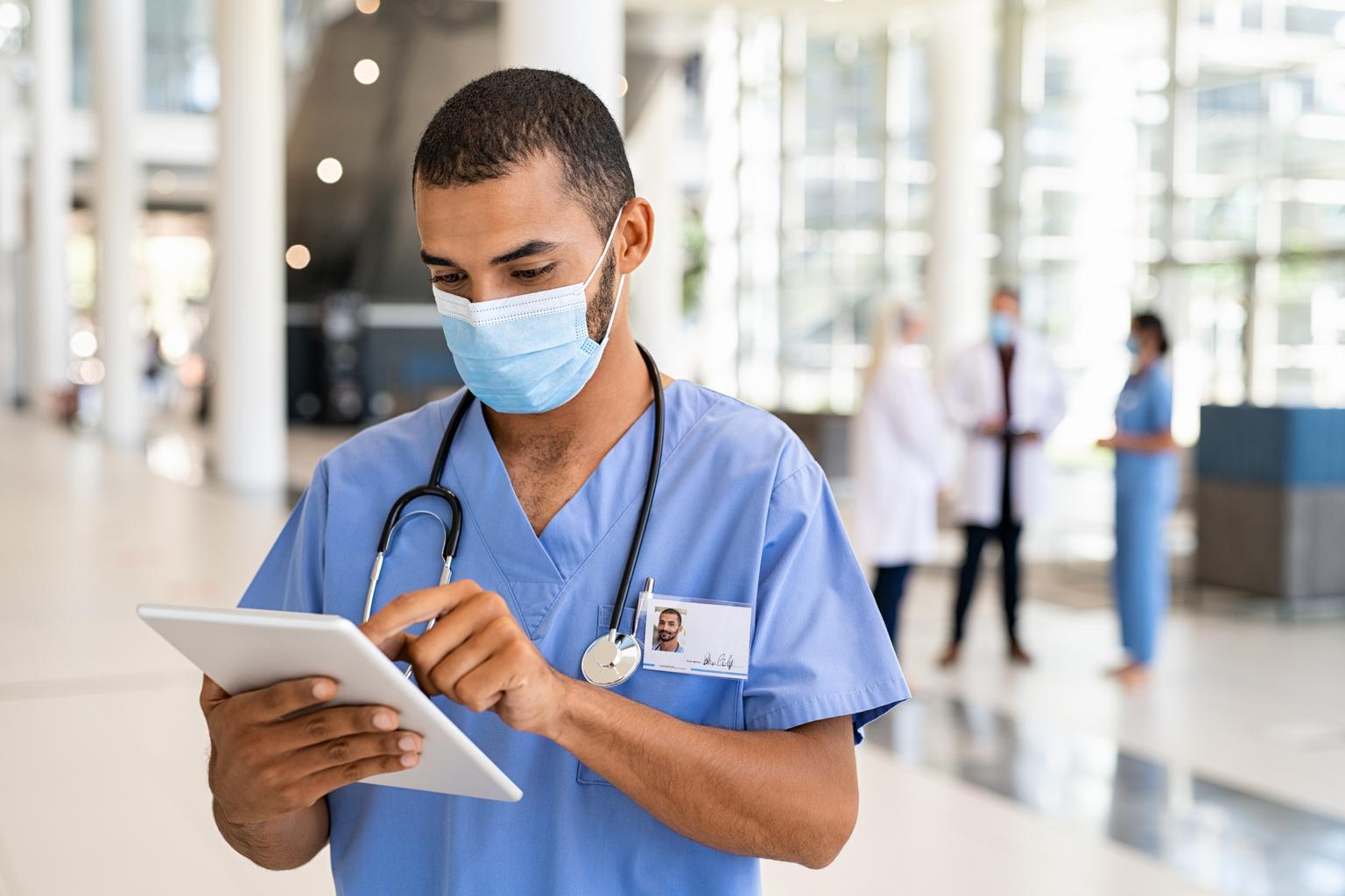 Diverse doctor in mask with tablet