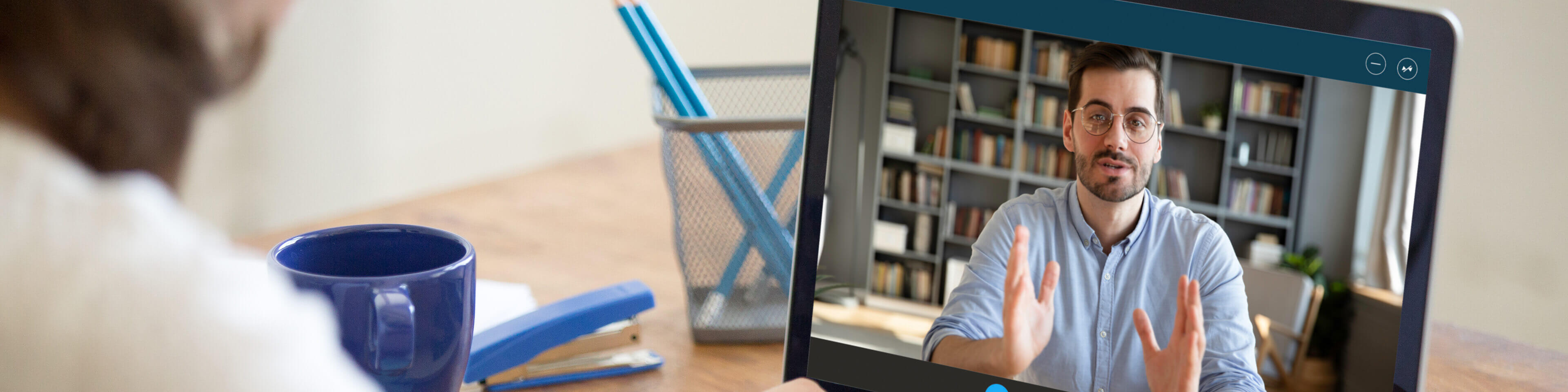 laptop open with a man on video on the screen. woman in the background.