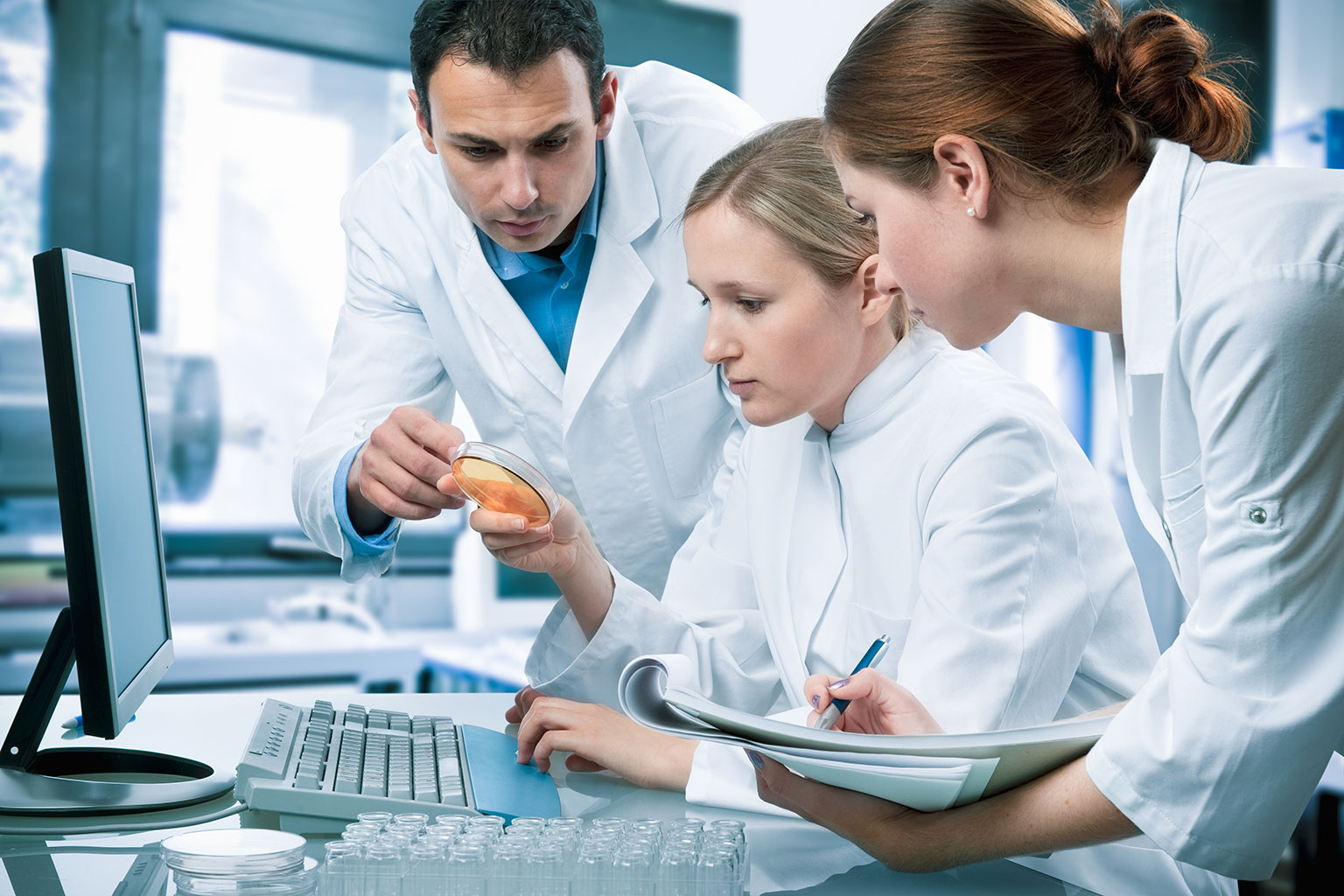 Researchers gathered around a petri dish and monitor