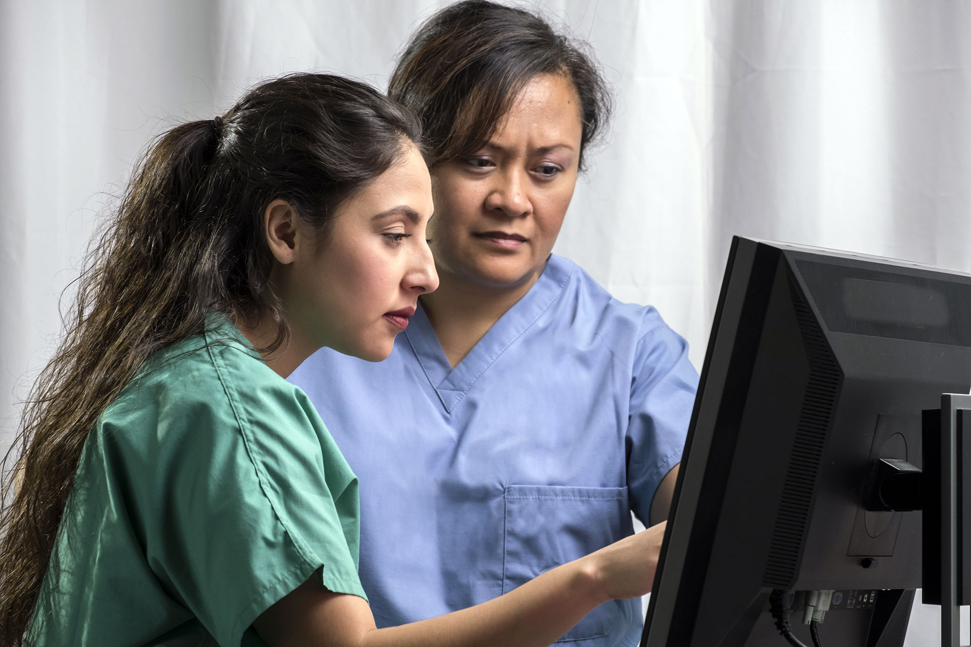 Two female nurses looking at a computer monitor