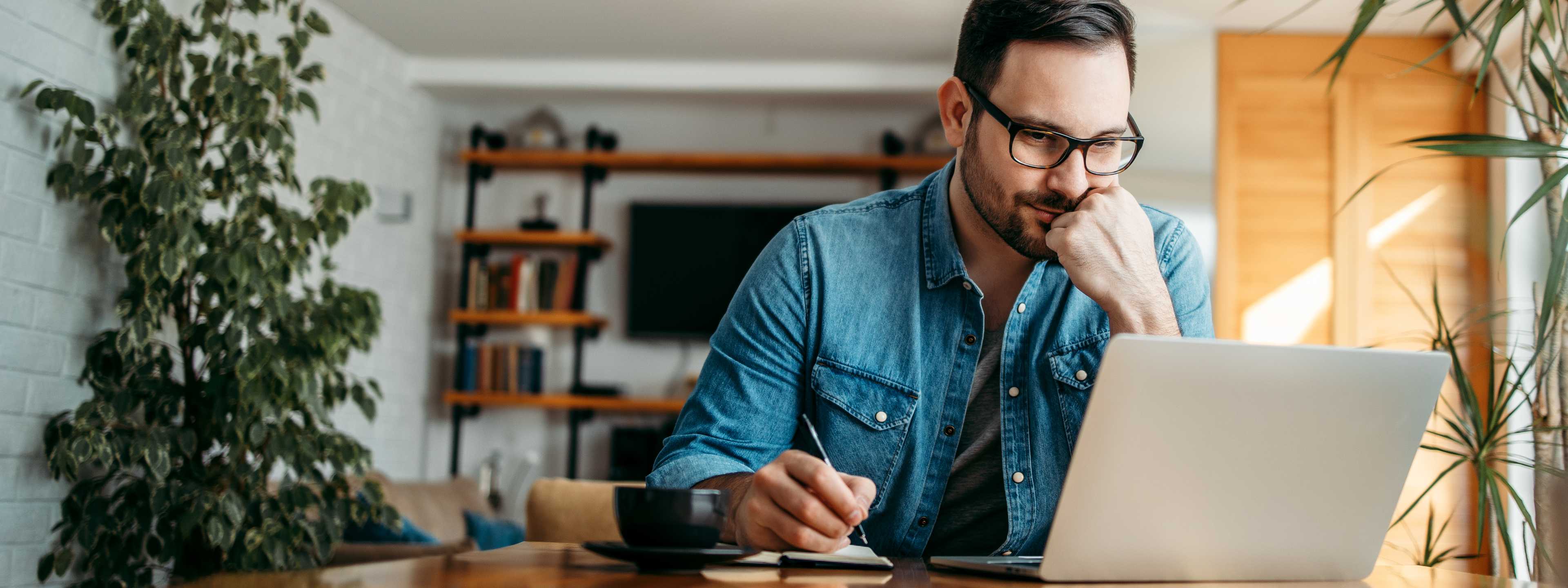 Man on laptop writing notes