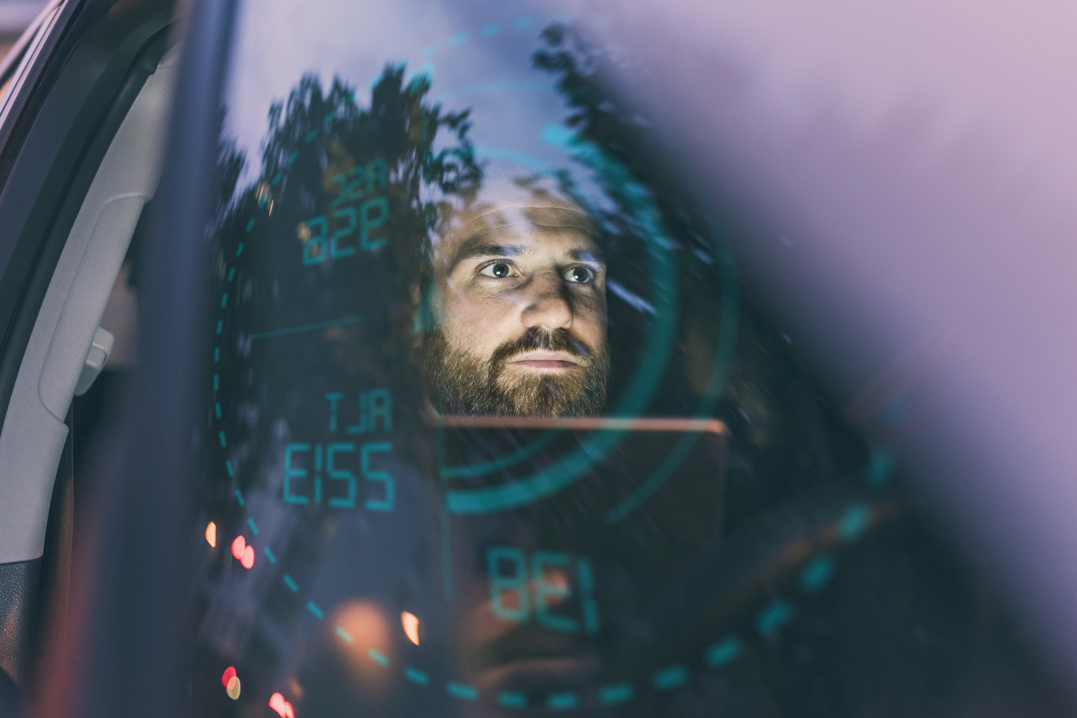 Focused man in car at night surrounded by dashboard projection