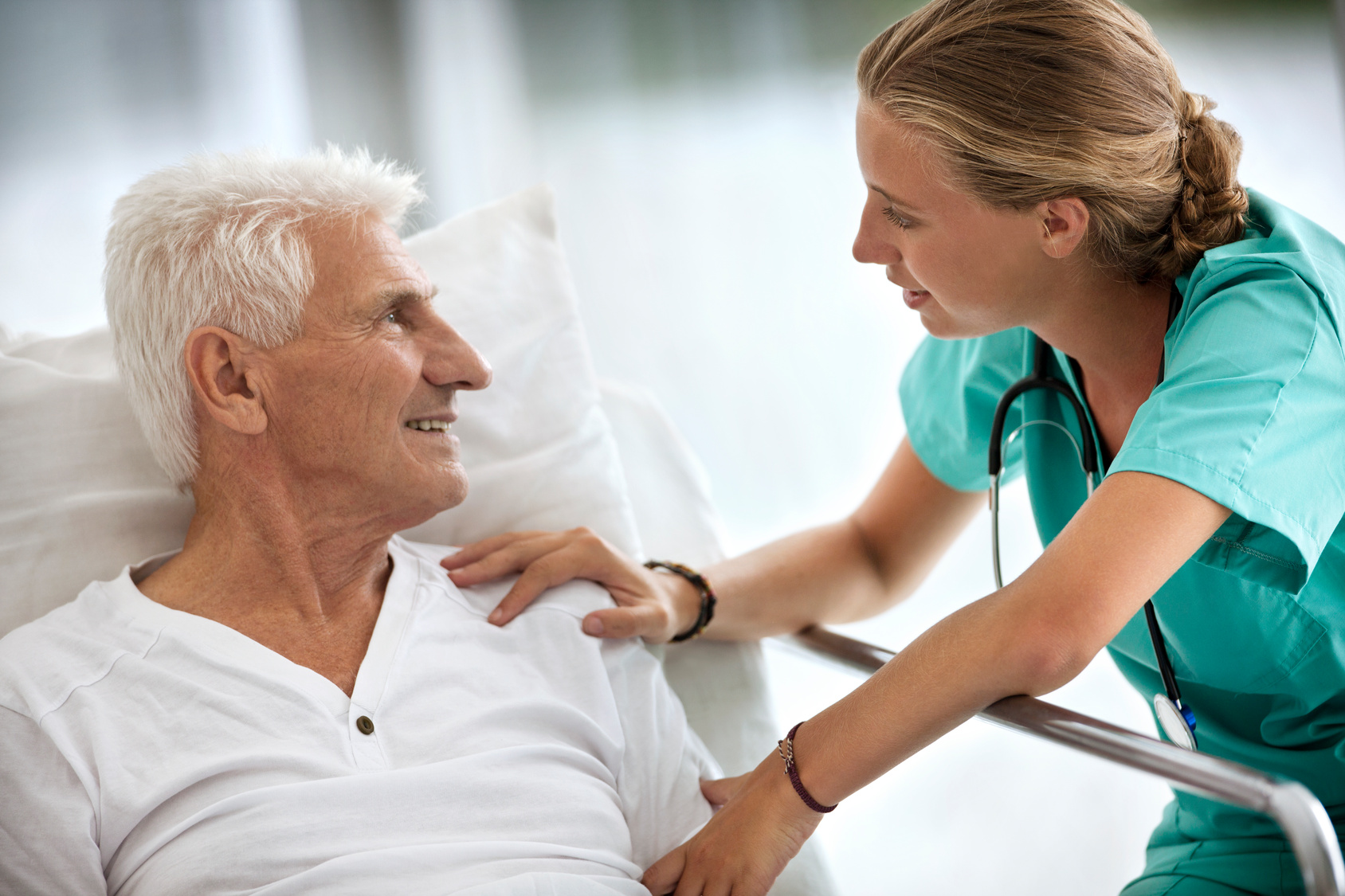 Nurse wearing green scrubs providing comfort to senior patient