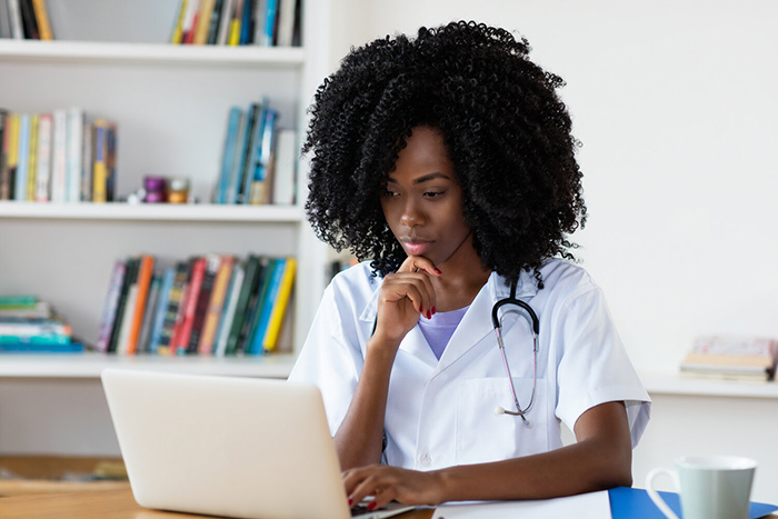 Nurse sitting at desk working on laptop