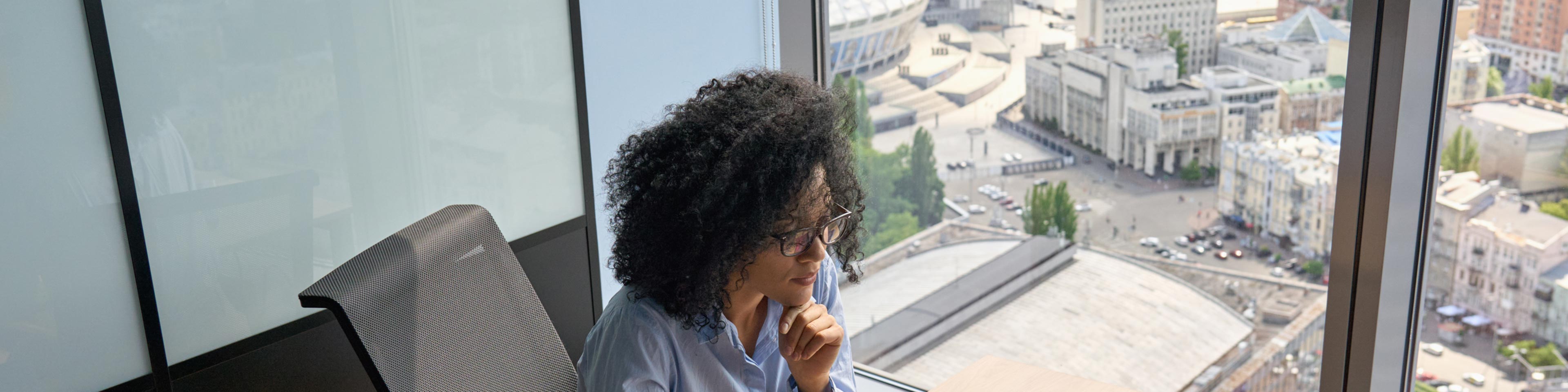 girl sitting at her desk by a window with a view of the city