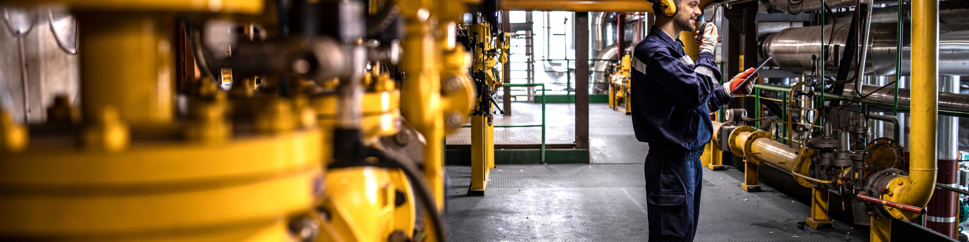 Petrochemical worker controlling process of crude oil production inside oil and gas refinery plant.