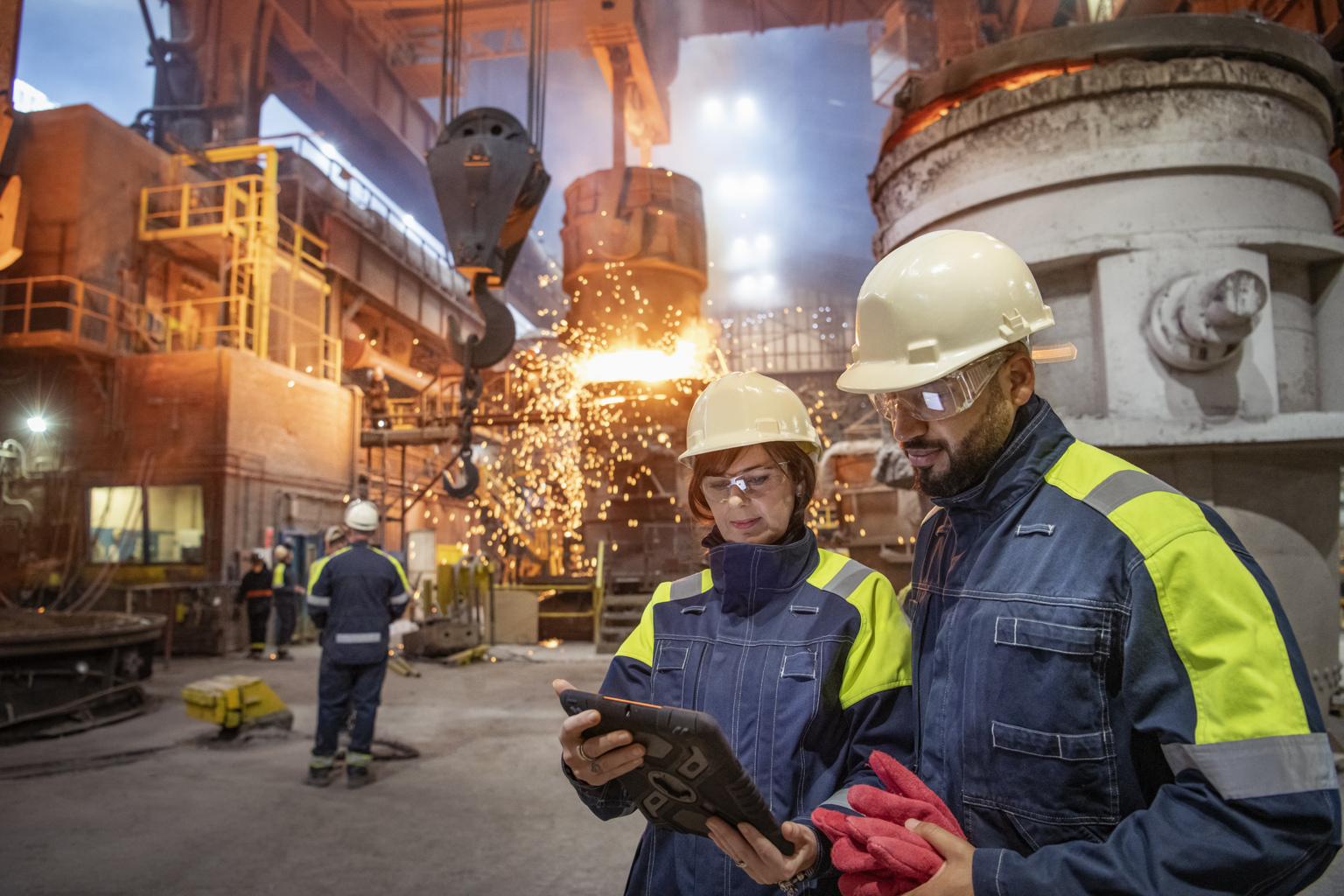Man and woman coworkers looking at the tablet at industrial facility in steel industry