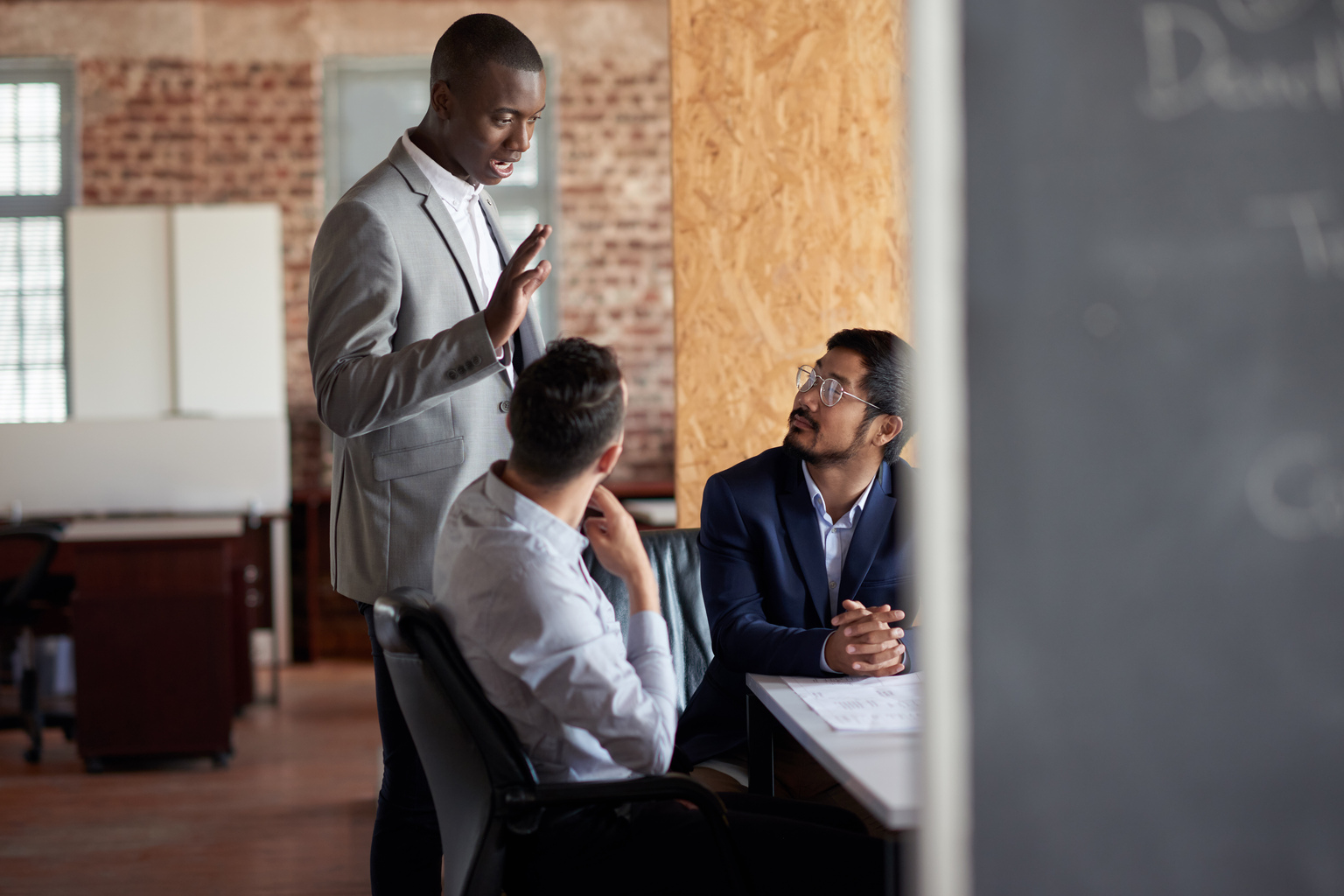 An African American employee standing and speaking with his colleagues