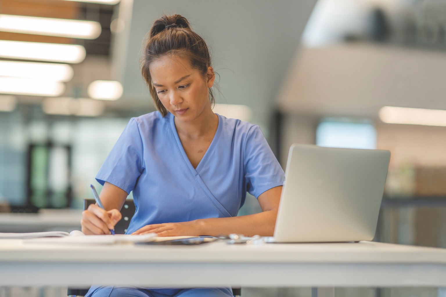 Nurse working at table with laptop