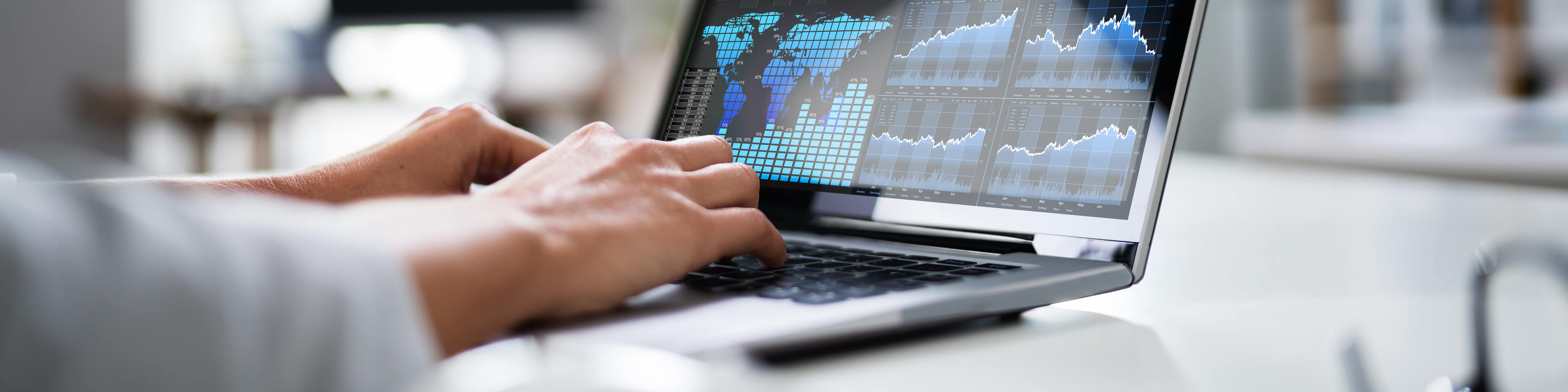 laptop screen showing charts and a world map in data, person typing on the keyboard