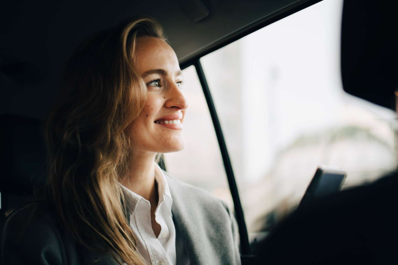 Business woman in car checking phone
