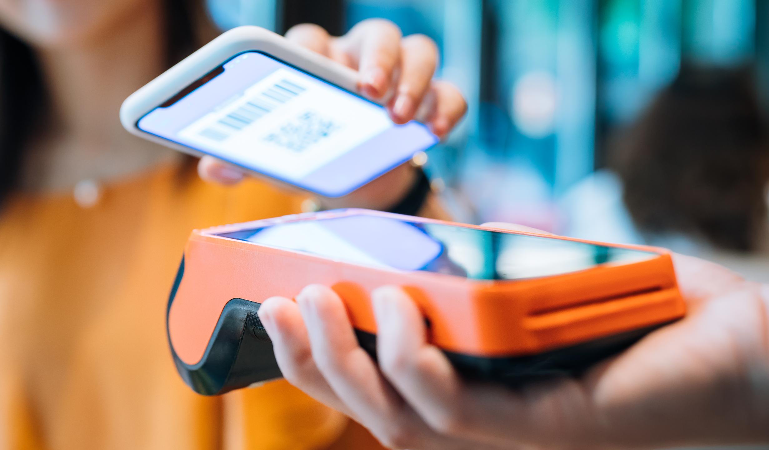 Young woman paying with smartphone in a cafe