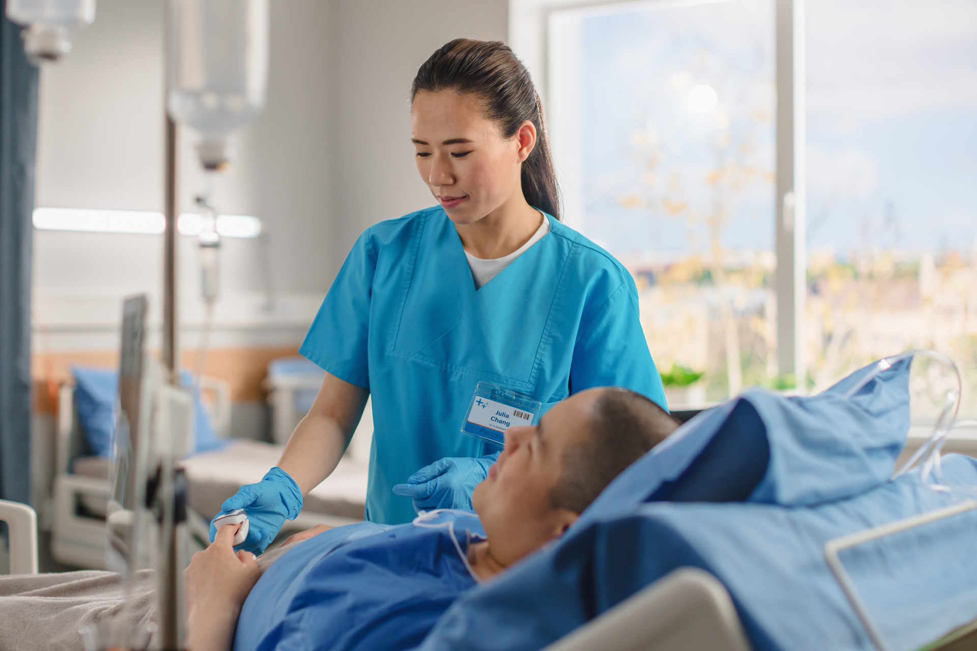 Nurse connects finger heart rate monitor to patient in bed