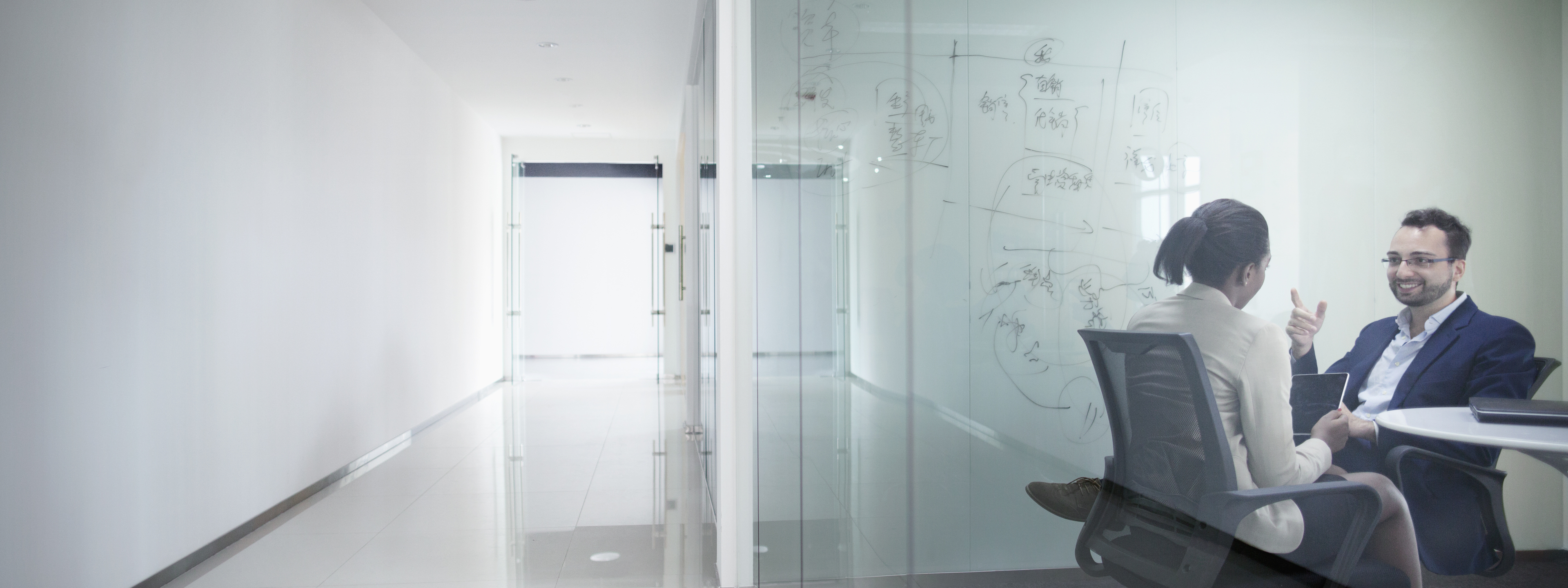 Pair of business colleagues sitting in modern contemporary glass meeting room