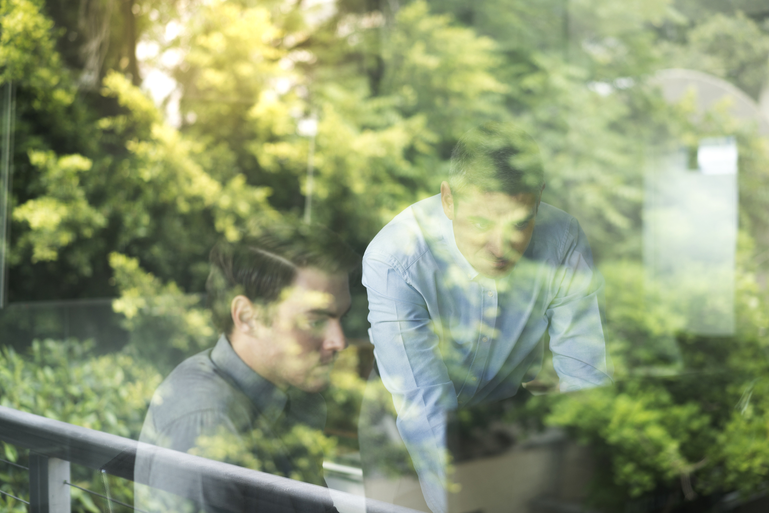 Businessmen using computer seen through window