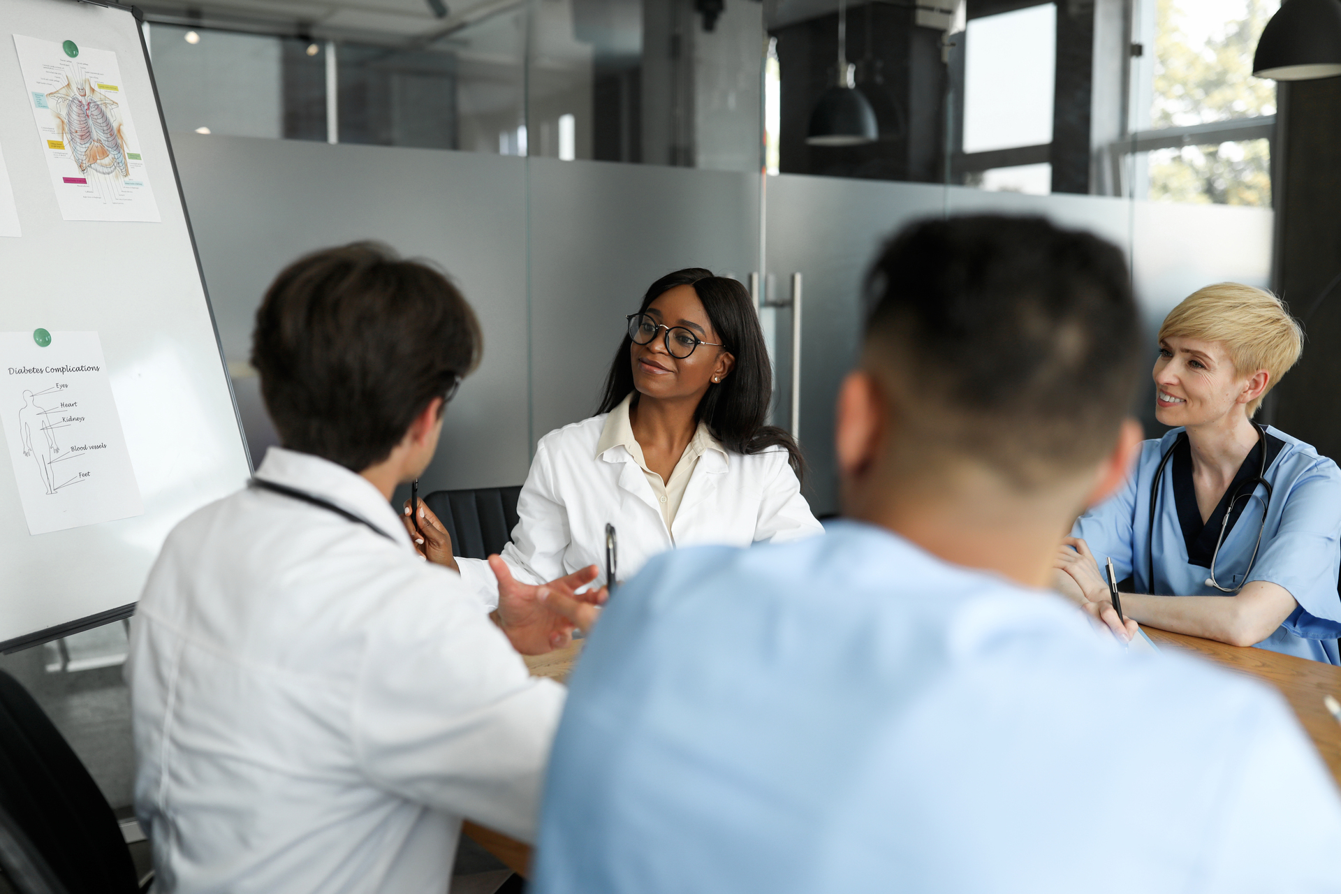 Group of medical professionals in a meeting considering information on a whiteboard