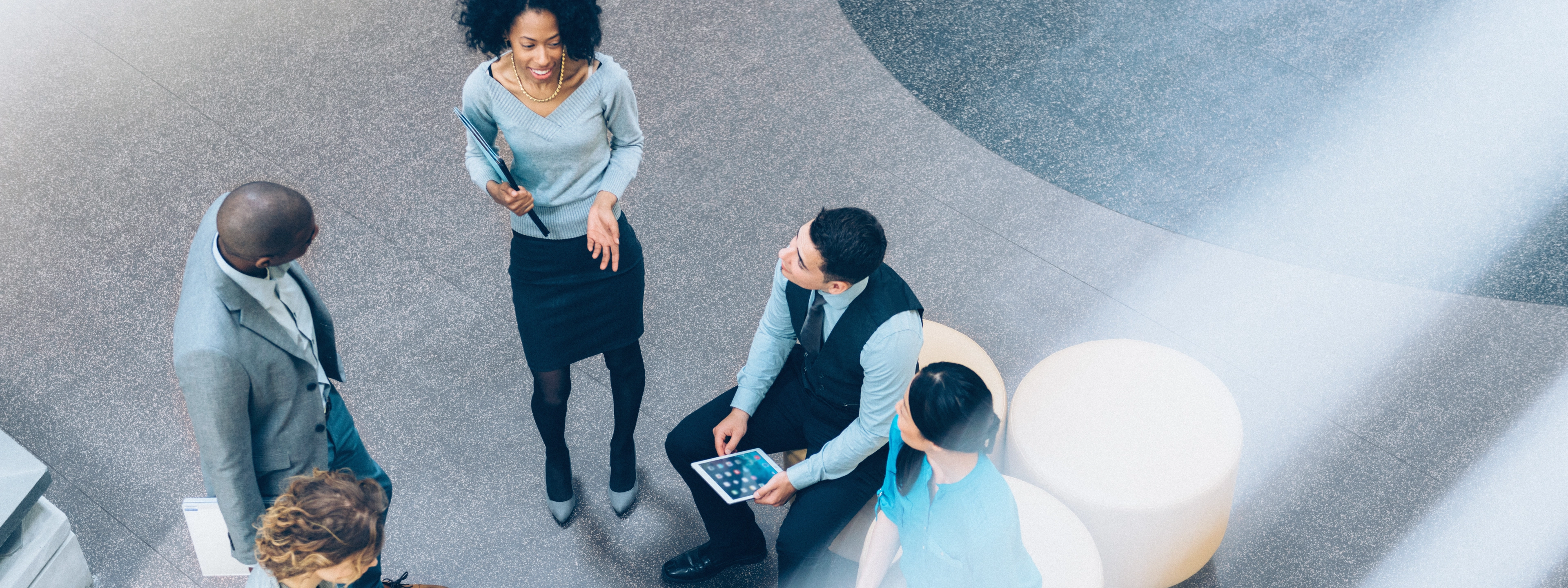 Five people of multiethnic background smiling and talking in the office lobby