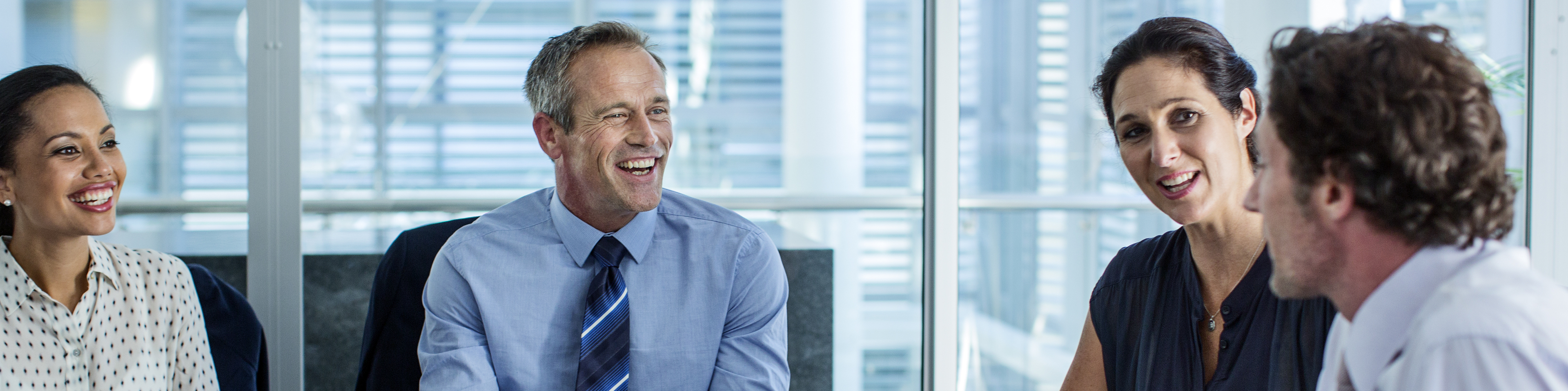 Happy business professionals discussing at conference table in office