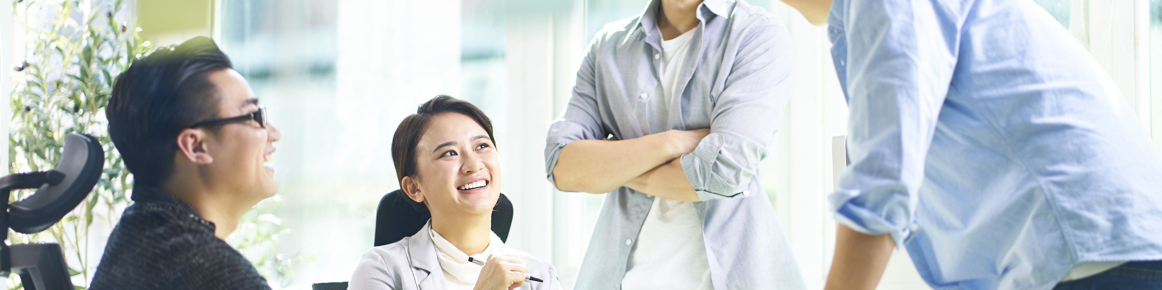 Group of four happy young Asian corporate people teammates meeting discussing business in office.