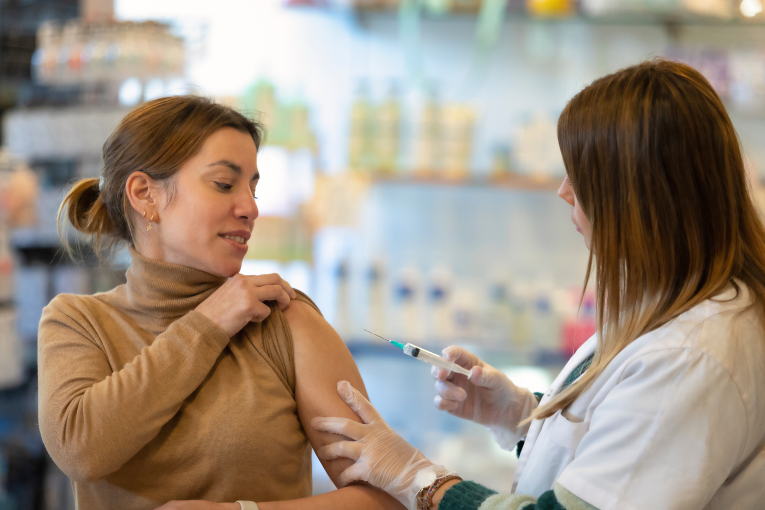 Woman patient receiving vaccine at pharmacy by pharmacist