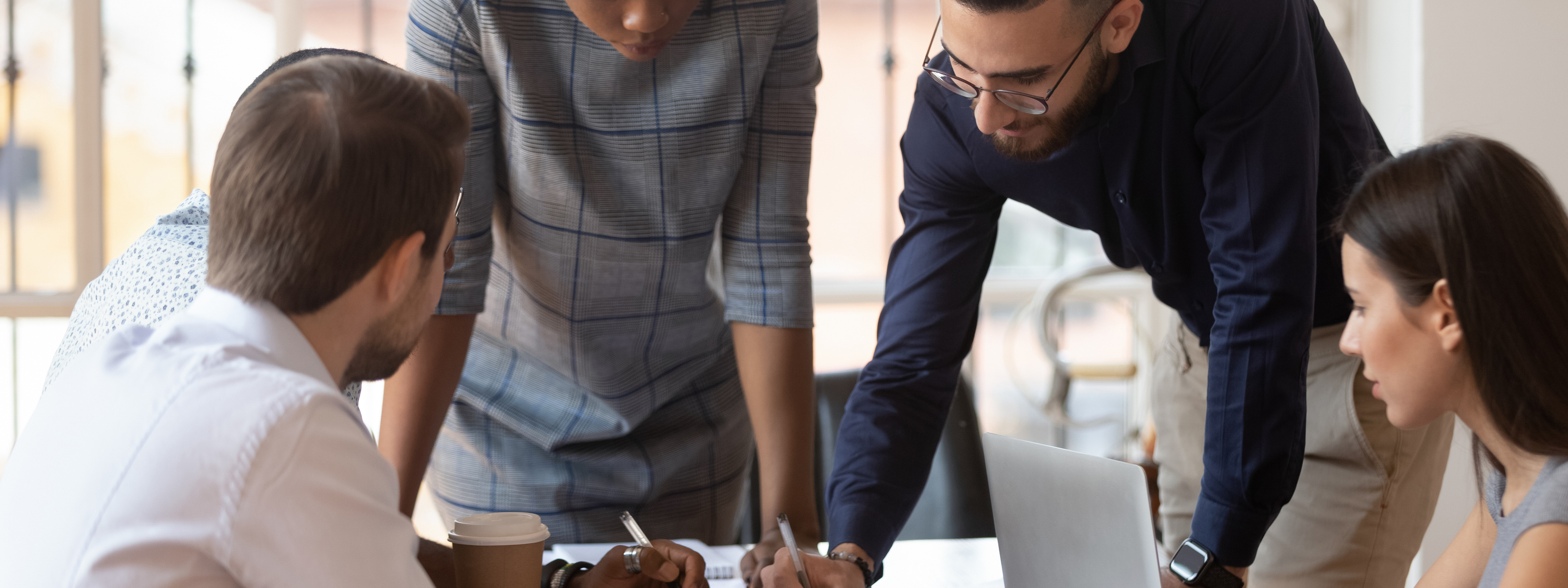 Focused multiracial corporate business team people brainstorm on marketing plan financial report gather at office table meeting, diverse serious colleagues group discuss paperwork engaged in teamwork