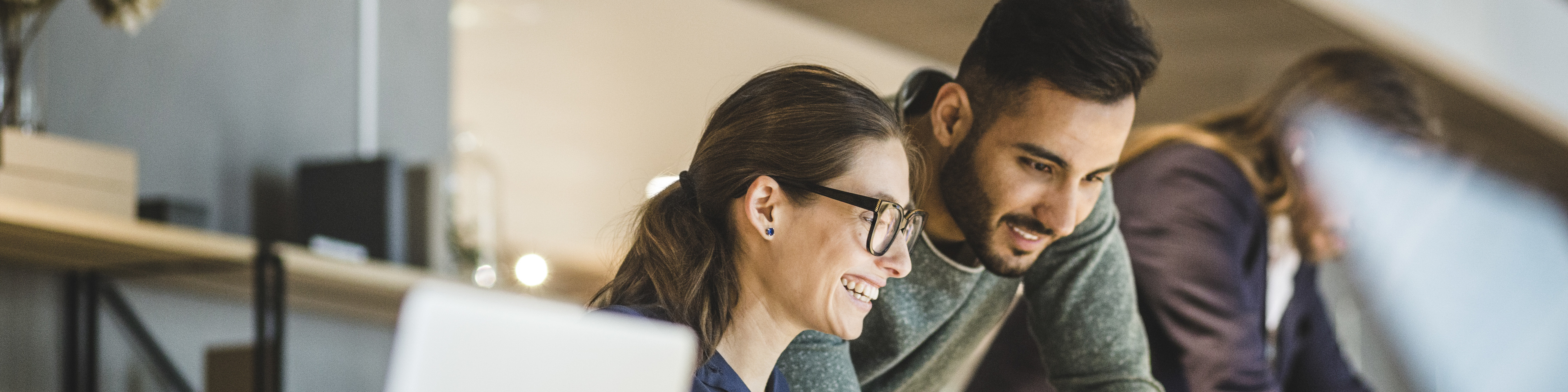 Coworkers smiling and working in a creative business with open office space.