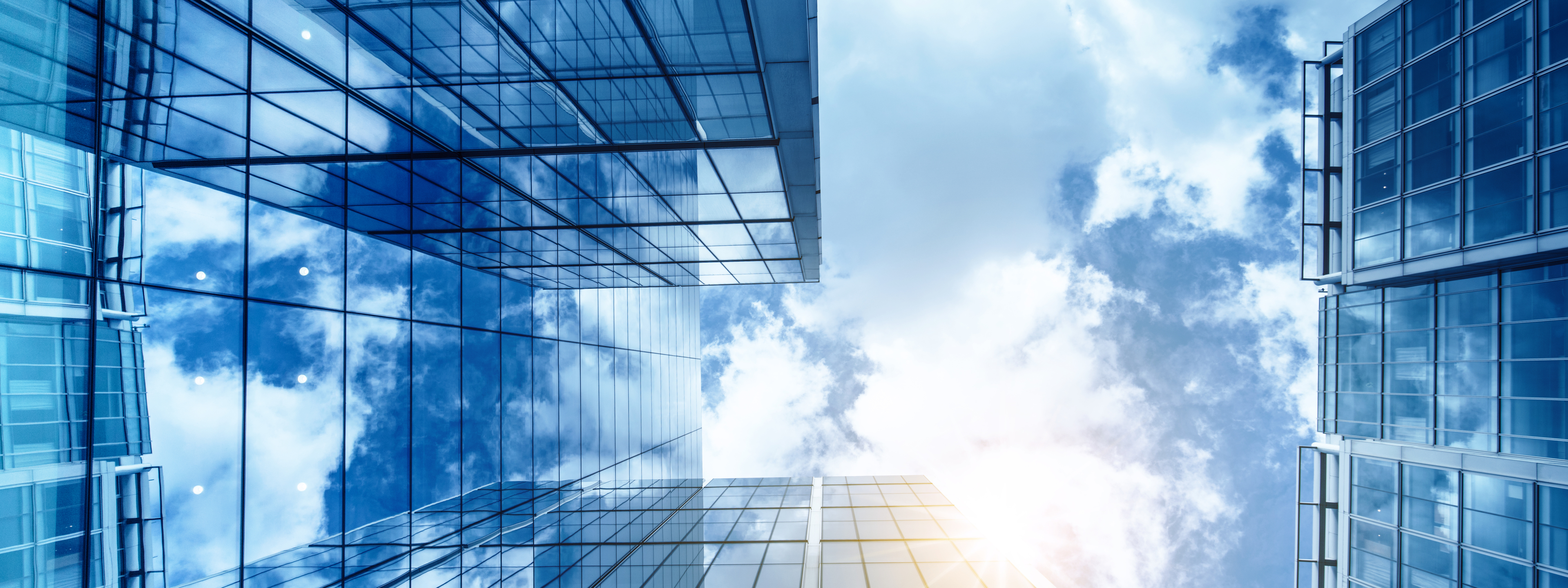 view of a contemporary glass skyscraper reflecting the blue sky