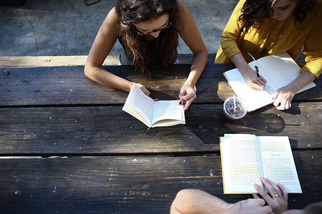 Birdseye view of three people sitting at picnic table studying