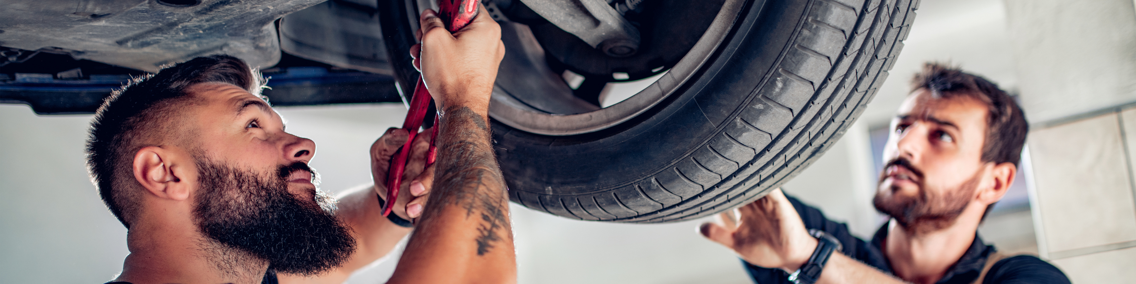 Two auto mechanics working on a car that is on the lift