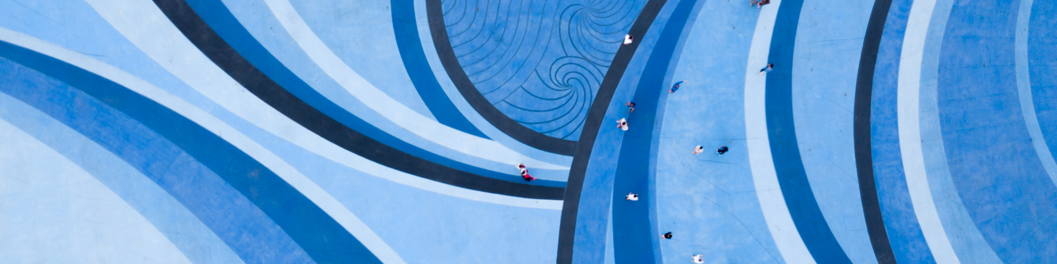 Aerial Drone View of People walking over a Circular Swirl Patterned Blue Floor,