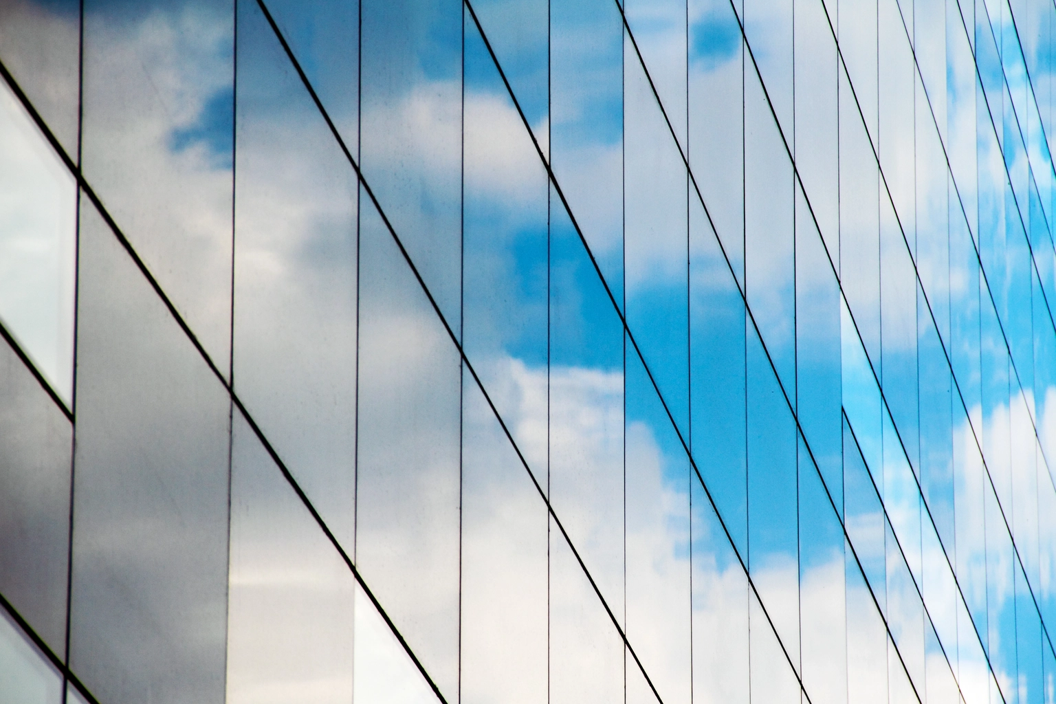 A reflection of clouds and sky in a mirrored glass building,