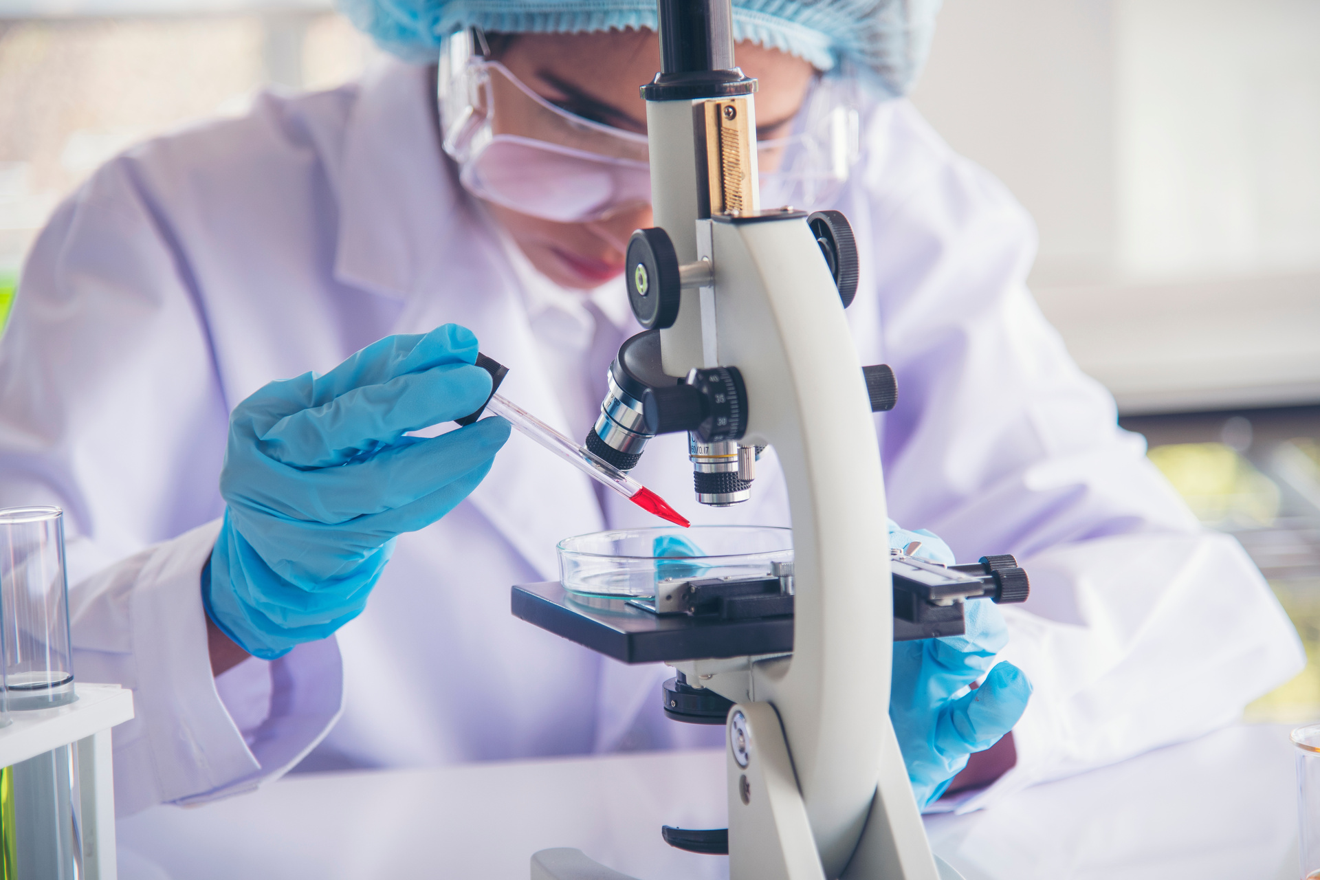 Medical researcher looking at sample through microscope