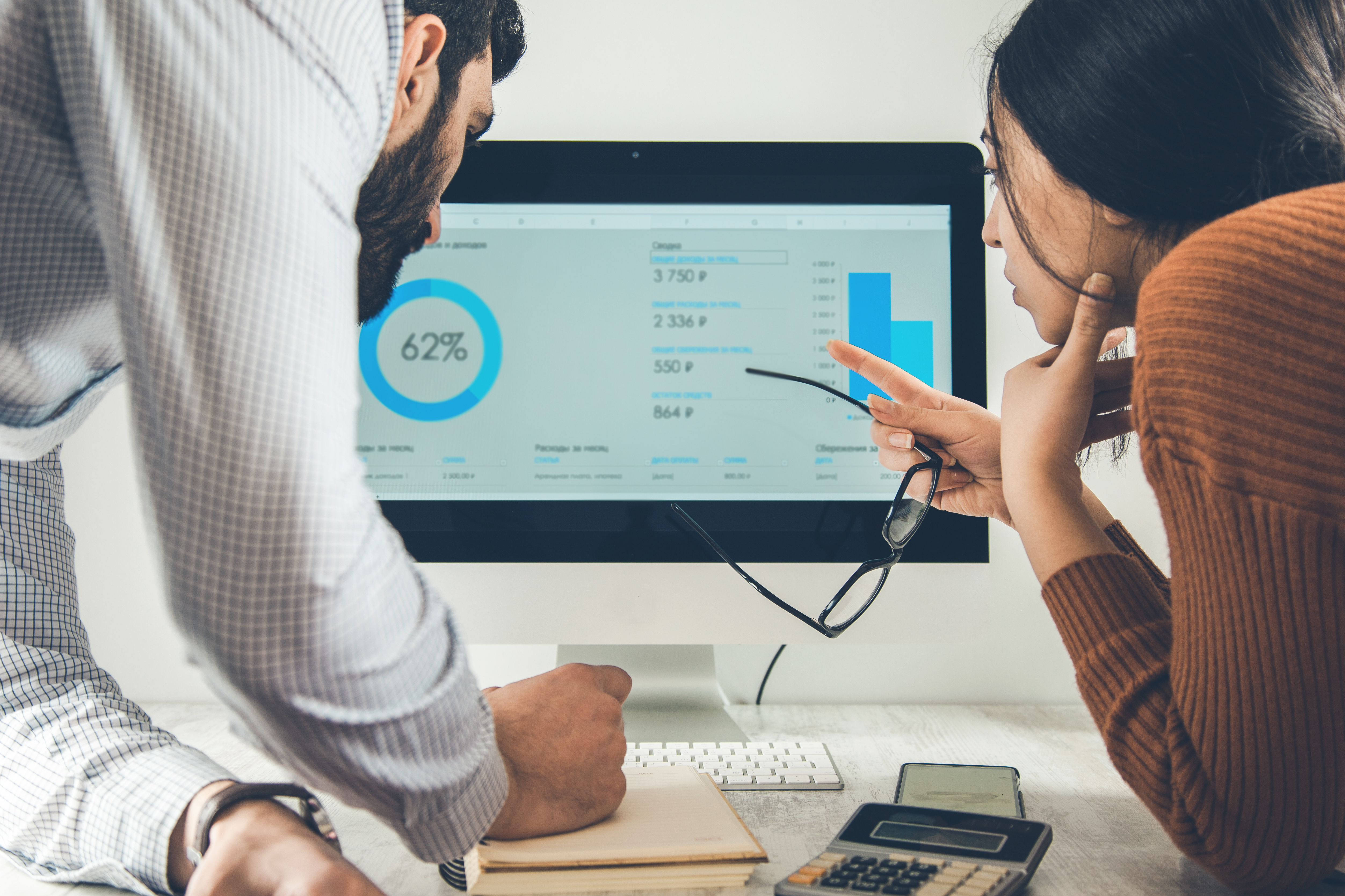 Two business professionals look at charts on a computer screen.